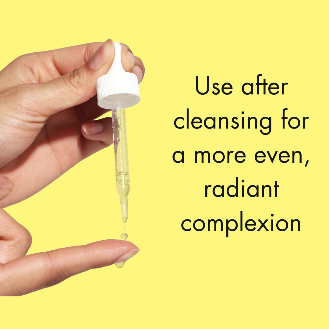 Hand holding dropper with vitamin c brightening serum with ferulic acid over finger on yellow background