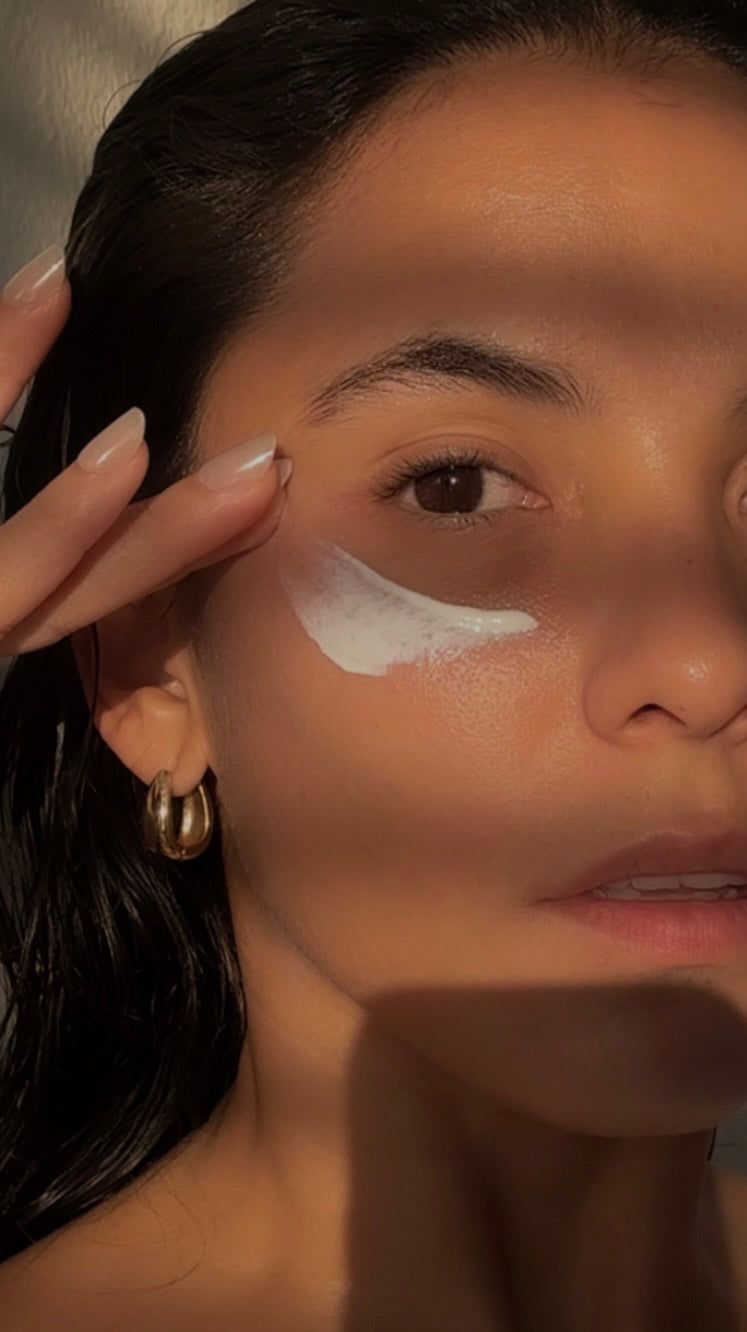 Close-up of woman applying sunscreen on face demonstrating layering serums under sunscreen technique