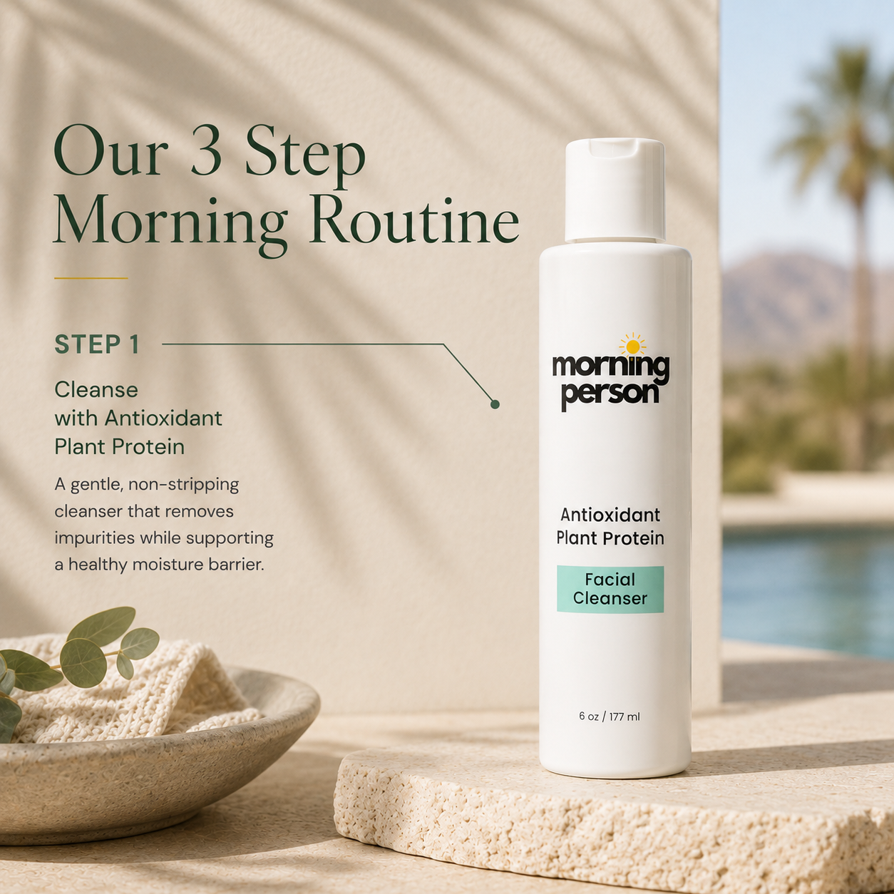 A white bottle of Morning Person Antioxidant Plant Protein Facial Cleanser stands on a stone pedestal in a sunlit setting with beach and palm trees in the background. Text on the left reads &
